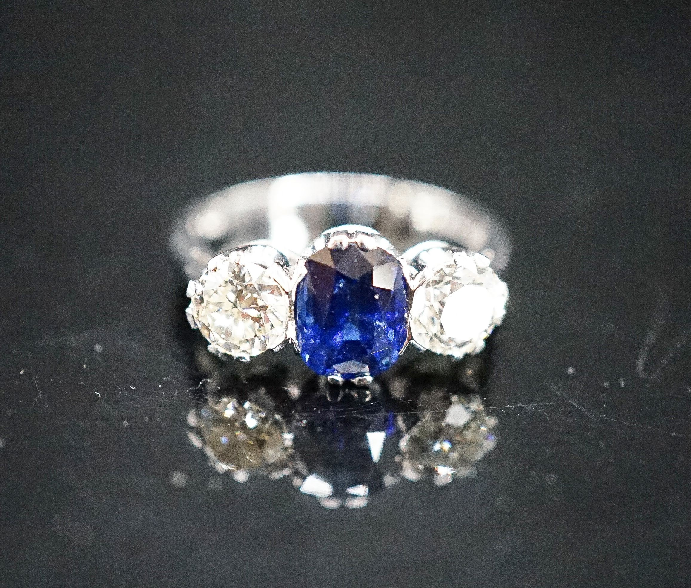 A modern 18ct white gold, single stone sapphire and two stone diamond set ring, size L, gross weight 4.2 grams